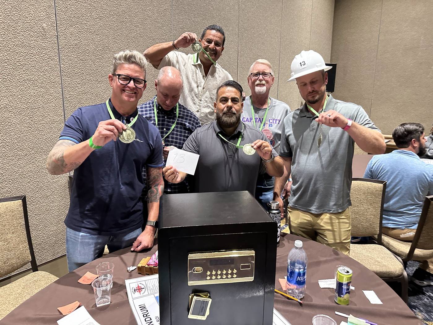 Five teammates celebrate with medals beside their escape-room case